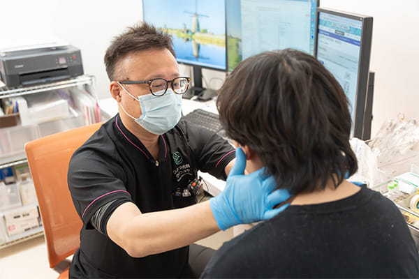 院長が患者さんに向き合い、マスクを着用して診察している様子