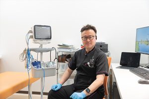 院長が診察室で説明している様子（マスク未着用）