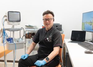 院長が診察室でこちらを向いて説明している様子